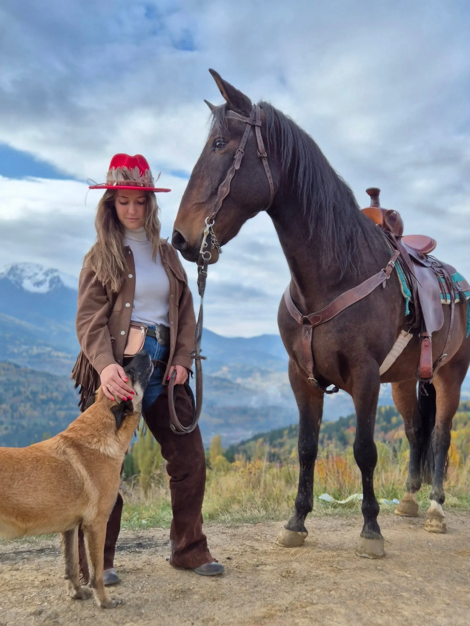 Mădălina, cu pălărie de cowboy roșie și haină de piele, lângă un cal maro înșeuat; Bruno stă la picioarele ei